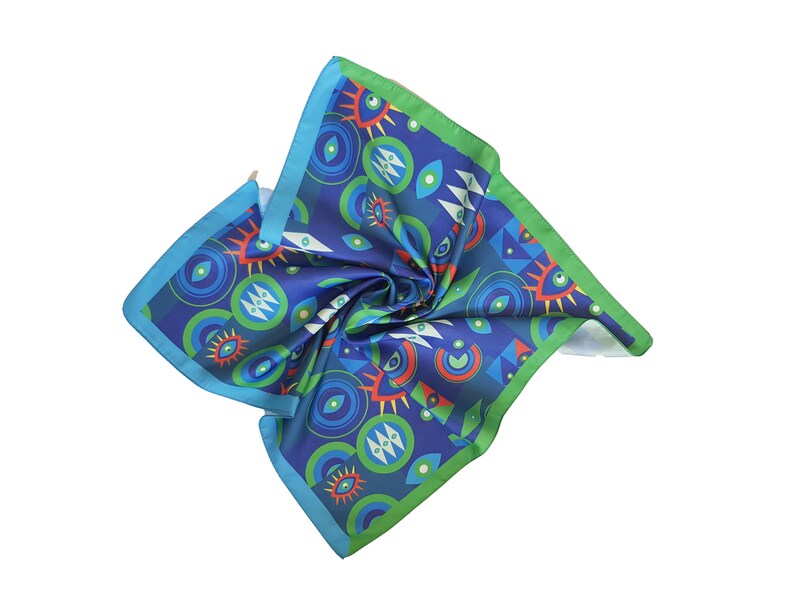 May include: A blue silk scarf with a green border and a colorful pattern of eyes and geometric shapes.
