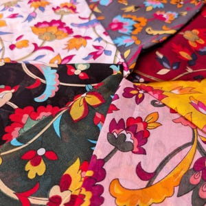 May include: A collection of colorful floral fabric swatches. The fabrics feature a variety of patterns with flowers in shades of red, yellow, pink, blue, and orange on backgrounds of white, black, gray, and burgundy. The fabrics are arranged in a circular pattern.