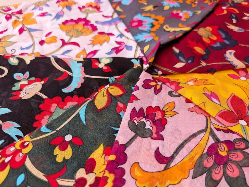 May include: A collection of colorful floral fabric swatches. The fabrics feature a variety of patterns with flowers in shades of red, yellow, pink, blue, and orange on backgrounds of white, black, gray, and burgundy. The fabrics are arranged in a circular pattern.