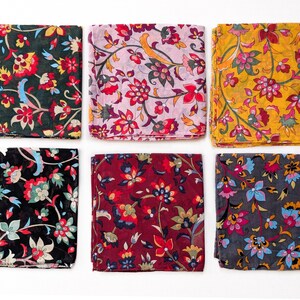 May include: Six folded square scarves with floral patterns. The scarves feature a variety of colors, including black, dark green, burgundy, yellow, and pink. Each scarf has a unique floral design with red, yellow, and blue accents.