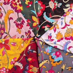 May include: A collection of colorful floral fabric swatches. The fabrics feature intricate designs with red, yellow, pink, and blue flowers on various backgrounds, including black, gray, and burgundy.