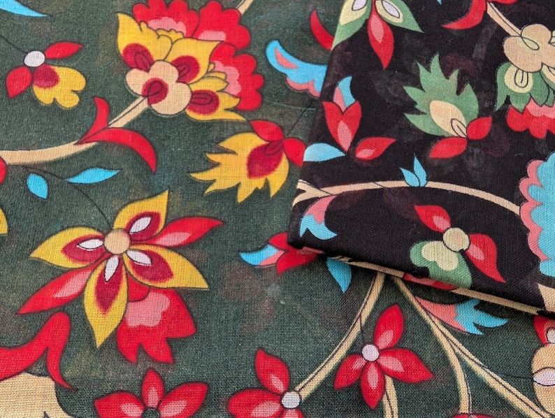 May include: Close-up of two pieces of fabric with a floral pattern. One piece is dark green with red, yellow, and white flowers. The other piece is black with a similar floral design in red, green, and blue.