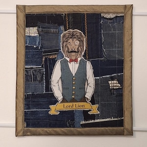 Könnte beinhalten: Gerahmtes Kunstwerk mit einer Löwenillustration in Weste, Fliege und Monokel. Der Hintergrund ist ein Jeans-Patchwork. Der Text "Lord Lion" befindet sich auf einem Banner. Der Rahmen hat einen braunen Rand.
