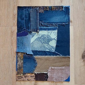 Könnte beinhalten: Ein Patchwork-Textilkunstwerk aus Jeansstoff und gemusterten Stoffen. Das Design zeigt eine Elefantenillustration auf hellgrünem Hintergrund, umgeben von verschiedenen Jeansstoff-Patches und strukturierten Materialien in Blau-, Braun- und Beigetönen.