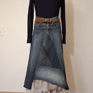 Puede incluir: Falda larga de mezclilla con diseño de patchwork, combinada con un jersey de cuello alto azul marino y un cinturón marrón. La falda se exhibe en un maniquí. La longitud de la falda es de aproximadamente 100 cm.