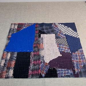 Könnte beinhalten: Ein Patchwork-Textil mit einer Vielzahl von Stoffen in Blau-, Lila-, Schwarz- und Mustertönen. Das Textil hat einen großen blauen Abschnitt und einen weißen Abschnitt mit einem Gittermuster.