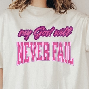Op de afbeelding: Wit T-shirt met een roze en paarse afbeelding met de tekst "my God will never fail."