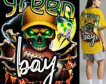 Op de afbeelding: Geel shirt met een groen en wit ontwerp met een schedel met een pet en een voetbal. De woorden "GREEN BAY" worden weergegeven in een gestileerd lettertype. Het ontwerp bevat bliksem en vlammen.
