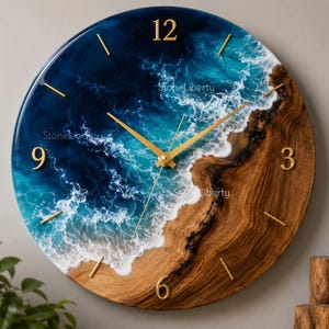 May include: A round wall clock featuring a glossy resin ocean design with deep blue and turquoise waves crashing against a natural wood grain shoreline. The clock face includes gold-colored numerals at 12, 3, 6, and 9, gold hands, and simple gold markers.