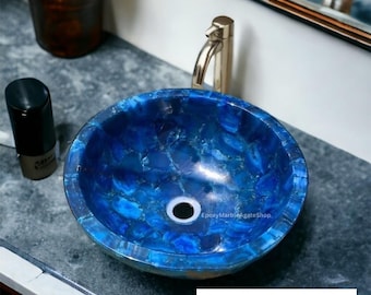 Pode incluir: Uma pia de ágata azul com um ralo branco. A pia é redonda e tem uma superfície texturizada. A pia é feita de pedra natural e tem um padrão único.