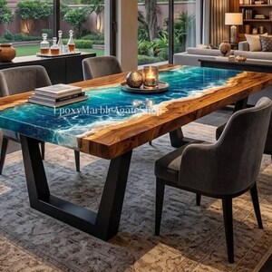 May include: A rectangular dining table with a unique design. The table features a wooden frame with a blue and white epoxy resin center, resembling ocean waves. The table is supported by black metal legs and surrounded by gray chairs.