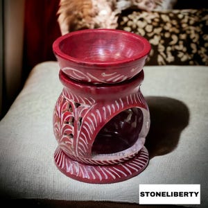 Peut inclure: Un brûleur à huile en pierre sculptée rouge et blanche avec un motif floral complexe. Le brûleur a un petit bol sur le dessus pour contenir des huiles essentielles ou des galets de cire.