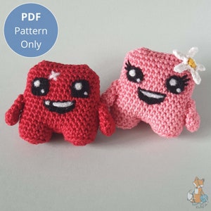 Op de afbeelding: Twee gehaakte pluche speelgoedjes, een rood en een roze, met lachende gezichten en zwarte ogen. Het roze speelgoed heeft een witte bloem op zijn hoofd.  Alleen PDF-patroon.