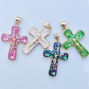 Peut inclure: Quatre pendentifs en forme de croix dorés avec un motif en mosaïque. Les croix sont rose, blanche, verte et irisée.