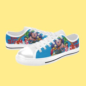 May include: White canvas low-top sneakers with a blue background featuring Lilo & Stitch characters. The text "Lilo & Stitch" is printed in red on the side of the shoes.
