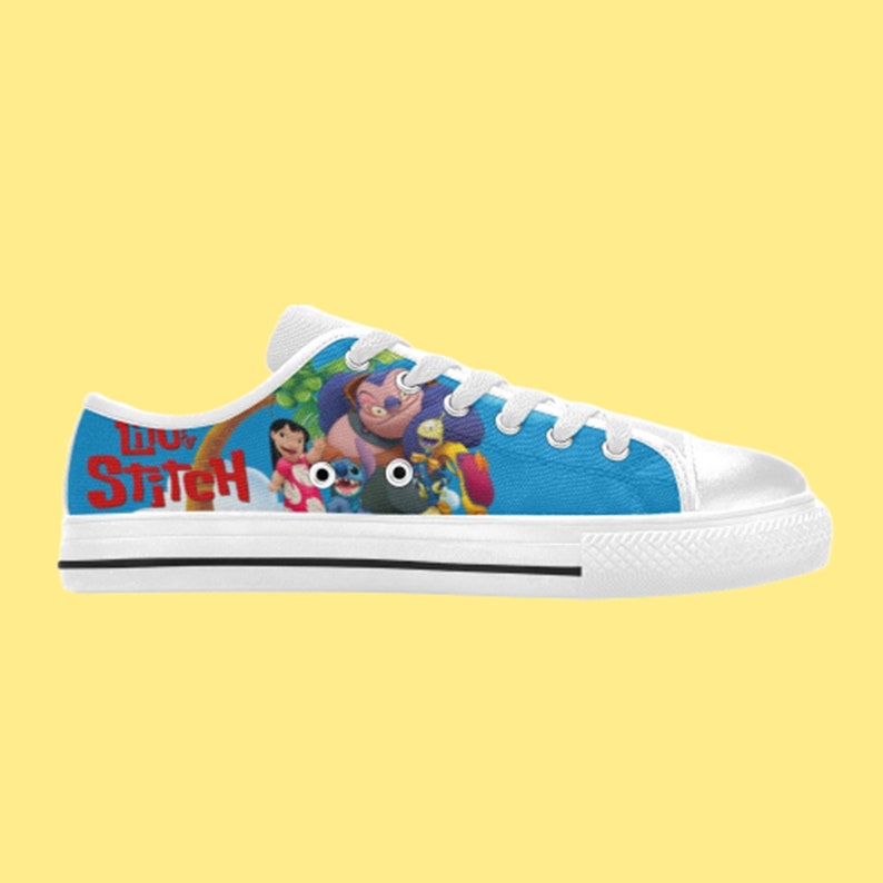 May include: White canvas low-top sneakers with a blue background featuring Stitch and other characters from the Disney movie Lilo & Stitch. The text "Lilo & Stitch" is printed in red on the side of the shoe.
