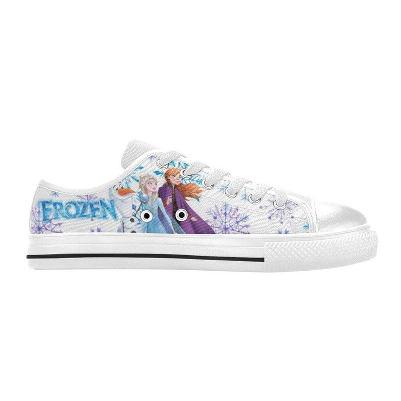 May include: White canvas low-top sneakers with a Frozen design. The sneakers feature a snowflake pattern and an image of Elsa and Anna from the movie Frozen. The word "FROZEN" is printed on the side of the sneakers.