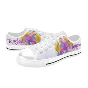 May include: White canvas low-top sneakers with a colorful illustration of Rapunzel from the movie Tangled. The shoes have purple text that says "Tangled" on both sides.