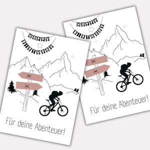 May include: Black and white birthday card with a mountain scene and a silhouette of a person riding a mountain bike. The card says "Happy Birthday" and "For your adventures!"