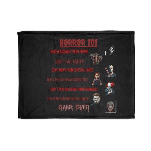 May include: Black fleece blanket with a red and white graphic of horror movie characters and the text "Horror 101" and "Game Over". The graphic includes the text "Never answer your phone", "Don't fall asleep", "Stay away from crystal lakes", "Dolls are not always good guys", "Don't take balloons from strangers", and "Stay home and hide on Halloween".