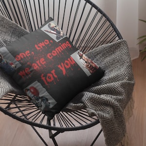 May include: Black throw pillow with a graphic print of horror movie characters. The text on the pillow reads "one, two, we are coming for you".