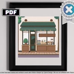 Op de afbeelding: Een digitaal kruissteekpatroon van een groene winkelgevel met een bruin afdak en een bord met de tekst "PDF". De winkelgevel heeft een groot raam met een etalage van goederen erin. Er staat een kleine boom voor de winkelgevel.
