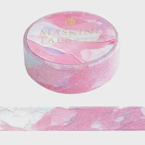 May include: A roll of masking tape with a pink, white, and light purple abstract watercolor pattern. The label on the top of the roll features the text MASKING TAPE and TSUTSUMU COMPANION in gold lettering, along with a small gold gift box icon.