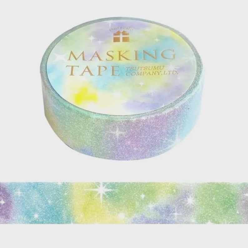 May include: A roll of masking tape featuring a pastel tie-dye pattern in shades of yellow, blue, and purple with a glittery finish and white starburst accents. The label on the top reads MASKING TAPE TSUTSUMU COMPANY, LTD. with a small gift icon.