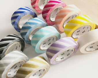 May include: A collection of twelve rolls of washi tape arranged in a grid, each featuring diagonal stripes in various colors including red, blue, pink, orange, yellow, black, gray, purple, and gold, with the brand name mt printed on the inner core.