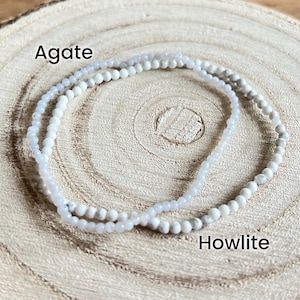 May include: A double-strand bracelet made of white howlite and light blue agate beads. The bracelet is on a wooden surface. The words "Agate" and "Howlite" are written below the bracelet.