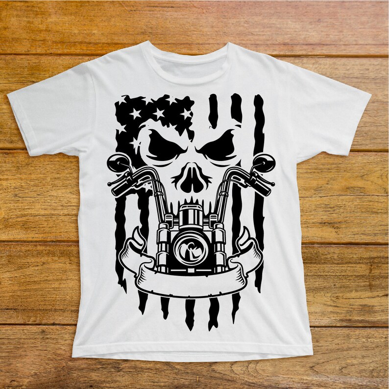 May include: White t-shirt with a black and white graphic of a skull with a motorcycle engine and handlebars. The skull is in front of an American flag.
