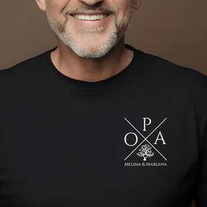 Puede incluir: Camiseta negra con un diseño gráfico blanco que presenta un árbol con las letras "POA" y el texto "Melina & Marlene" debajo.