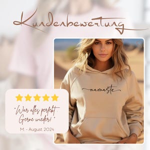 K&ouml;nnte beinhalten: Ein beiger Hoodie mit dem Wort "namaste" in schwarzer Kursivschrift auf der Vorderseite. Der Hoodie wird von einer Person mit langen braunen Haaren modelliert. F&uuml;nf gelbe Sterne sind unter dem Text "War alles perfekt. Gerne wieder!" sowie den Initialen "M", dem Monat "August" und dem Jahr "2024" zu sehen.