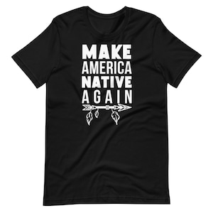 May include: Black t-shirt with the white text "MAKE AMERICA NATIVE AGAIN" stacked vertically. Below the text is a white arrow with feathers and leaves. The shirt is made of a soft material.