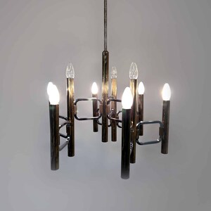 Può includere: Un lampadario in ottone con otto lampadine. Il lampadario ha un design moderno con un motivo geometrico.