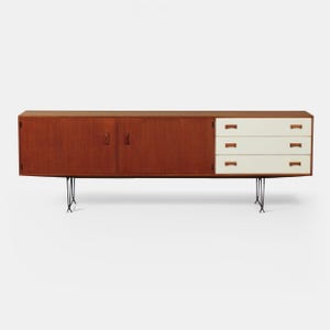 Op de afbeelding: Een dressoir in mid-century modern stijl met een warme houten afwerking. Het heeft twee deuren, drie witte lades en een contrasterend bovenblad. De kast wordt ondersteund door zwarte metalen hairpin poten, wat zorgt voor een strak, minimalistisch ontwerp. Ongeveer 180 cm lang.