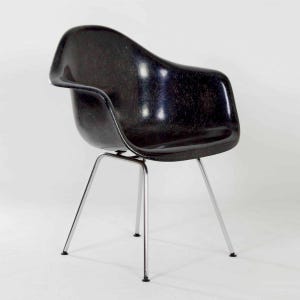 May include: A black fiberglass chair with a chrome frame. The chair has a curved back and a slightly angled seat.