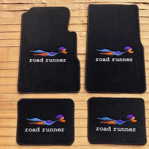 May include: Set of four black car floor mats with embroidered Road Runner logos. The Road Runner is a cartoon character from the Looney Tunes series.