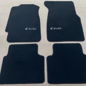 May include: Set of four black car floor mats with the word "Civic" embroidered in white on two of the mats.