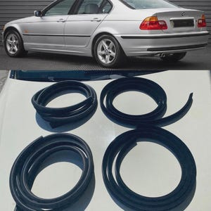 May include: Four black rubber door seal weatherstripping coils designed for a silver BMW 3 Series sedan. These flexible automotive components are coiled into circular shapes and feature a molded profile for installation along vehicle door frames.