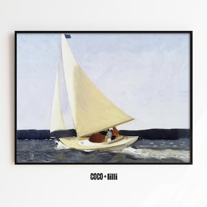 May include: A framed art print featuring a painting of a sailboat with cream-coloured sails on dark blue water under a pale sky. The boat carries two figures and leaves a white wake. The text COCO + lilli is printed below the black-framed image.