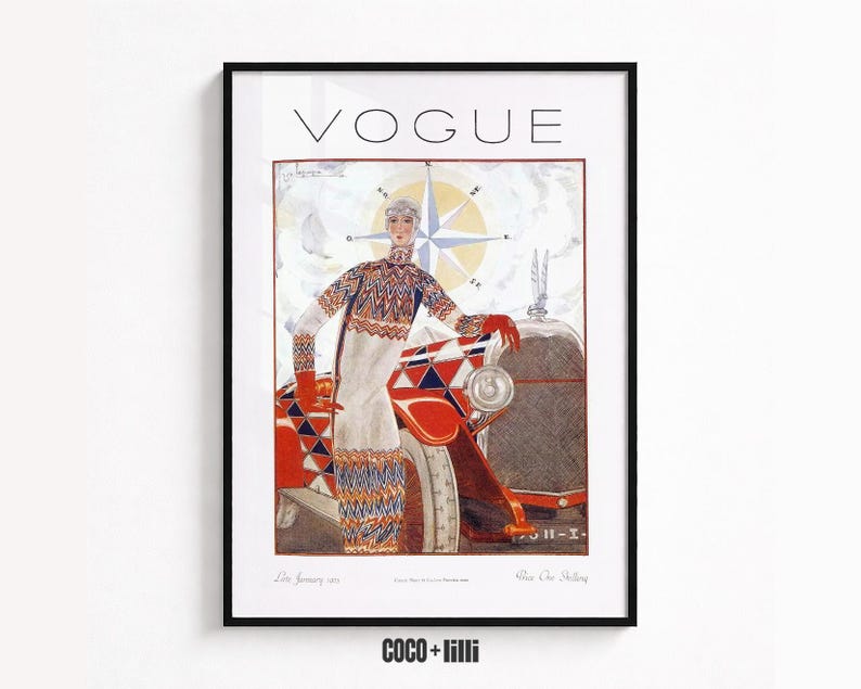 Op de afbeelding: Een ingelijste print van een Vogue-tijdschriftomslag uit januari 1925 met een persoon in een trui en rok met patroon naast een rood-witte auto met een kompasroos op de achtergrond. De tekst VOGUE staat in het zwart bovenaan gedrukt.