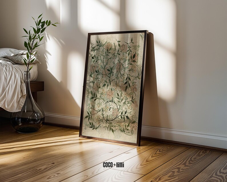 May include: A rectangular framed wall art piece featuring a botanical print with intricate green leaves, thin brown stems, and soft pink floral clusters on a light beige background. The text COCO + lilli is printed in black at the bottom center.