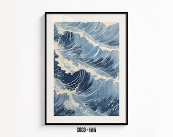 May include: A framed wall art print featuring a stylized illustration of turbulent ocean waves in shades of deep blue, light blue, and cream. The artwork displays swirling water patterns with white foam crests. The text COCO + lilli is visible.