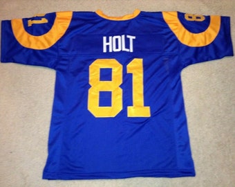 Könnte beinhalten: Ein blaues Footballtrikot mit gelben Verzierungen und der Nummer 81 auf der Rückseite. Der Name "HOLT" ist über der Nummer gedruckt.