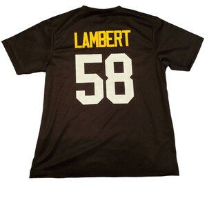 May include: Black t-shirt with the name "LAMBERT" and the number "58" printed on the back in white and yellow.