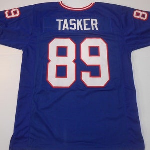 May include: A blue football jersey with white and red trim. The number 89 is on the back of the jersey with the name "TASKER" above it.