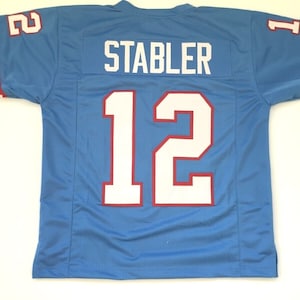 May include: A light blue football jersey with white and red trim. The number "12" is on the back of the jersey with the name "STABLER" above it.