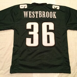 May include: Green football jersey with white lettering. The jersey has the name "WESTBROOK" and the number "36" on the back.