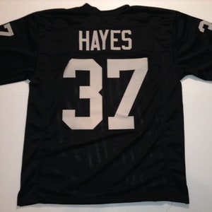 May include: Black football jersey with white lettering. The jersey has the name "HAYES" and the number "37" on the back.